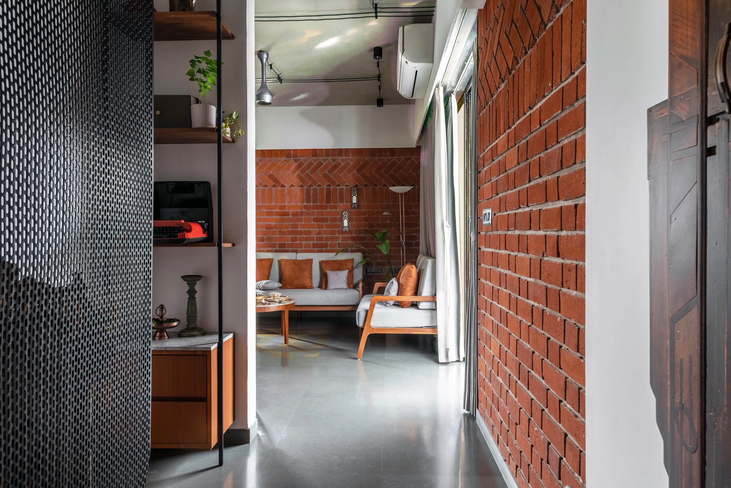 The entry passage, where perforated metal and exposed brick frame the first view into the living room