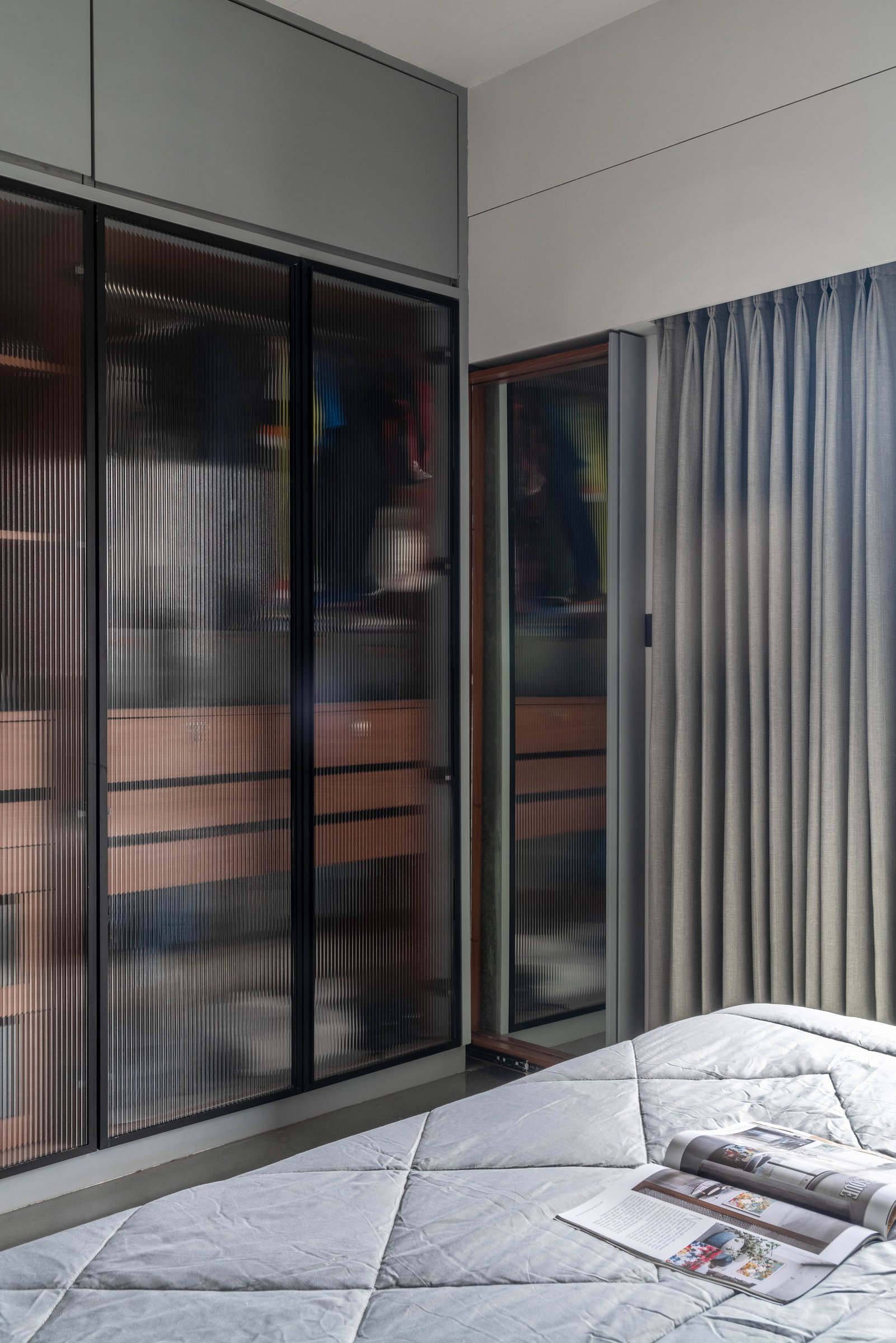 Fluted glass wardrobe doors in the master bedroom, softening storage into texture