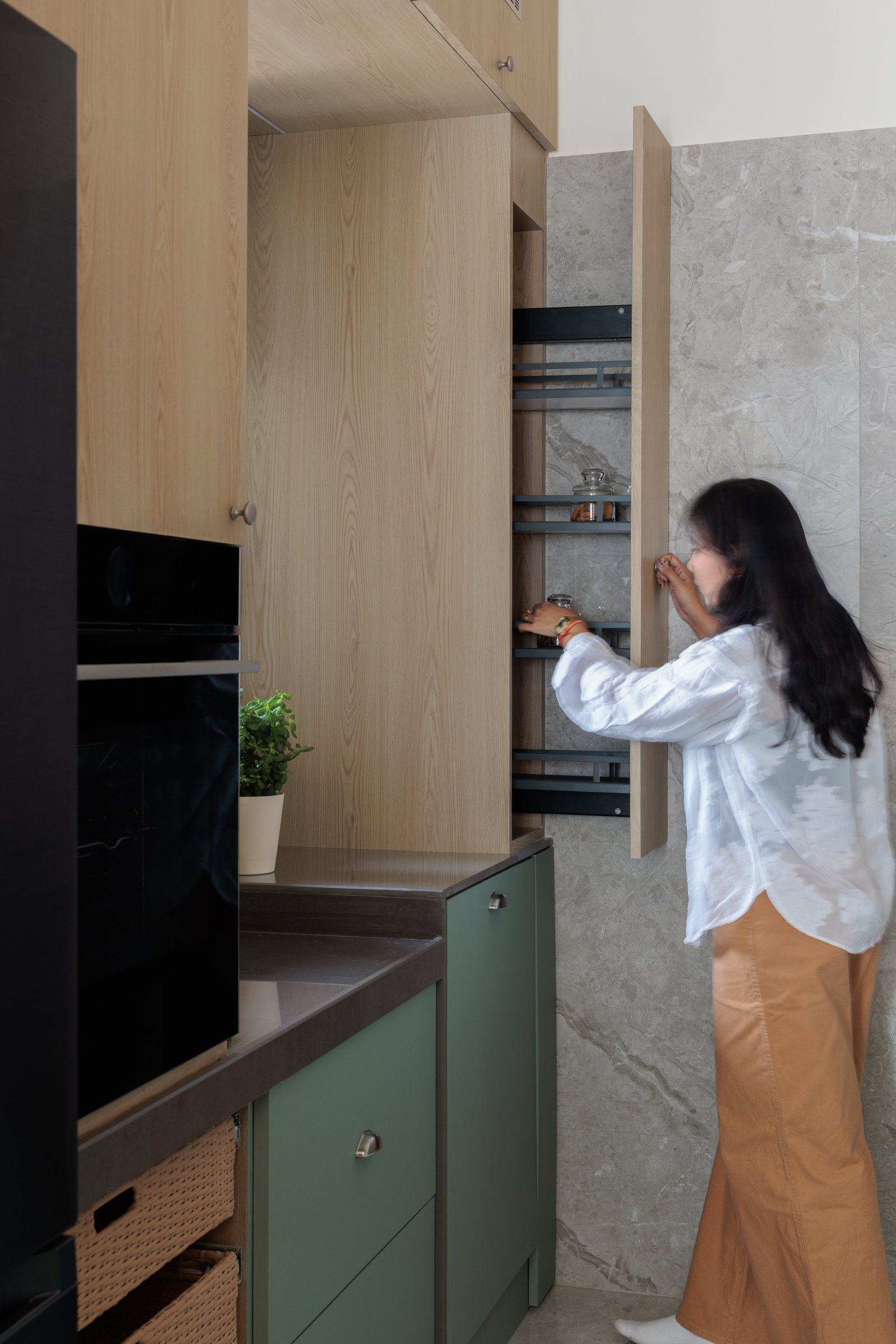 Kitchen storage in use, with pull-out organisers and a tall larder unit that demonstrate the planning behind the home's sense of sufficiency