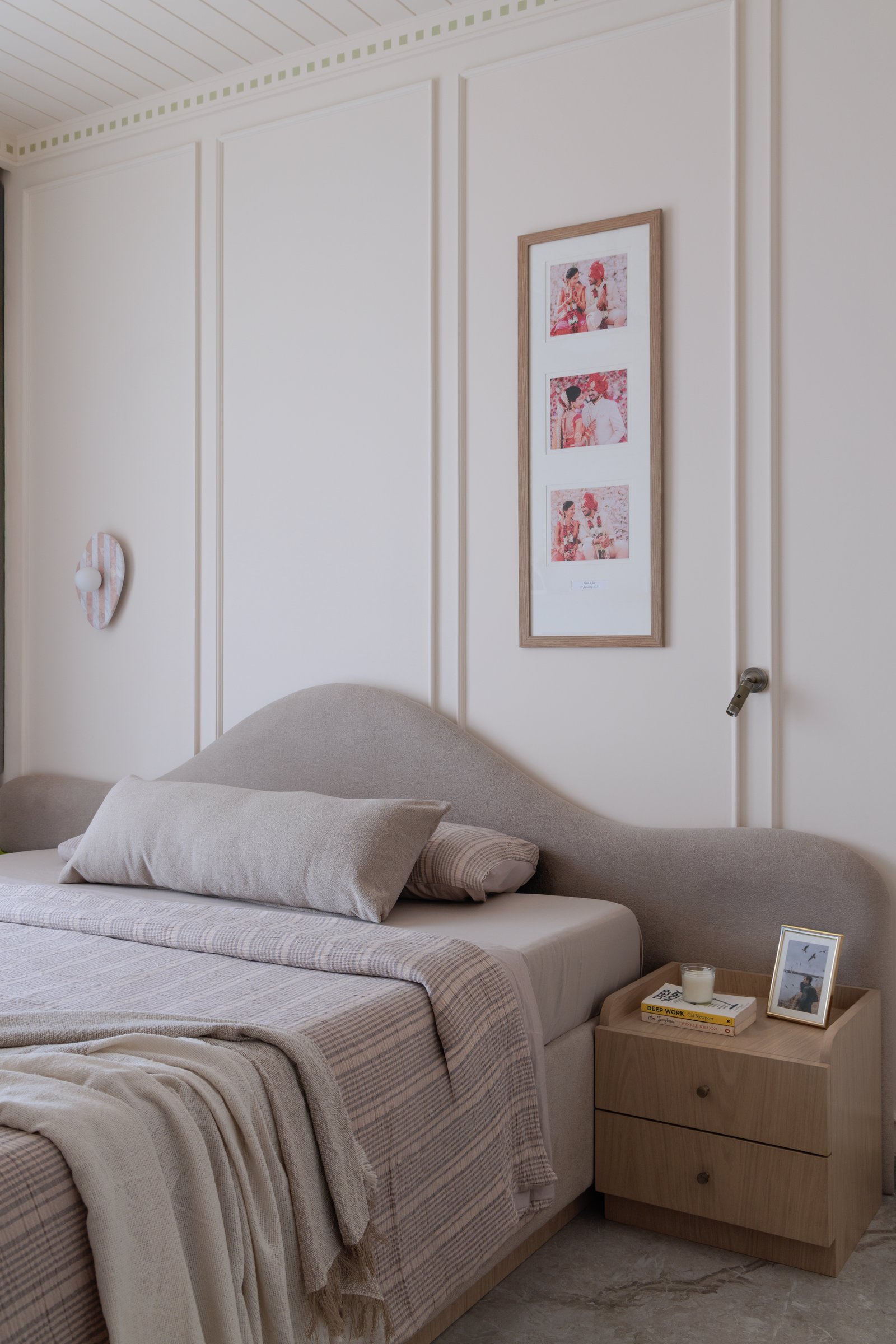 The bedroom, where a curved upholstered headboard and panelled walls continue the home's language of soft geometries