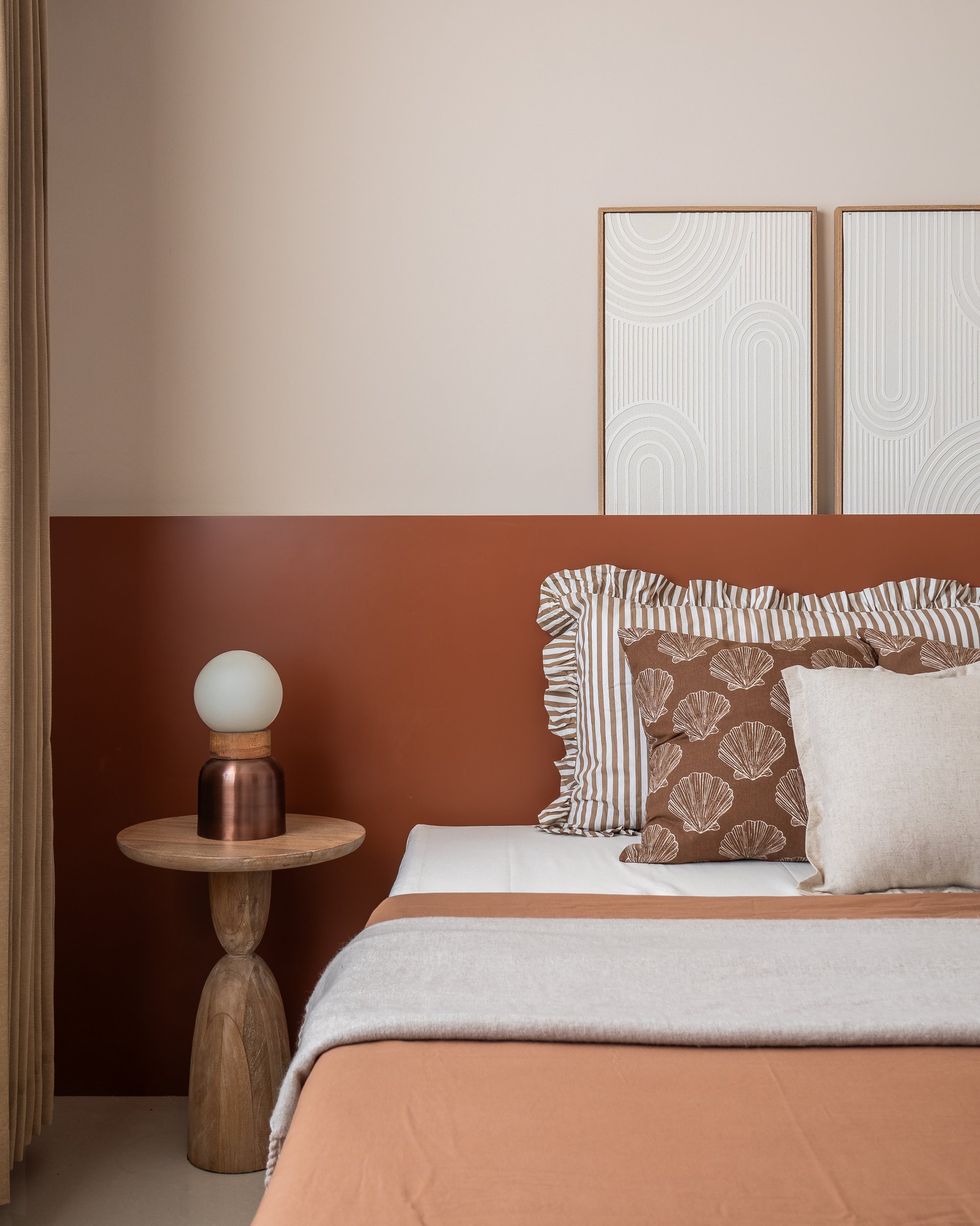 The second bedroom's terracotta half-wall creates a bold horizontal datum, making a small room feel deliberately composed