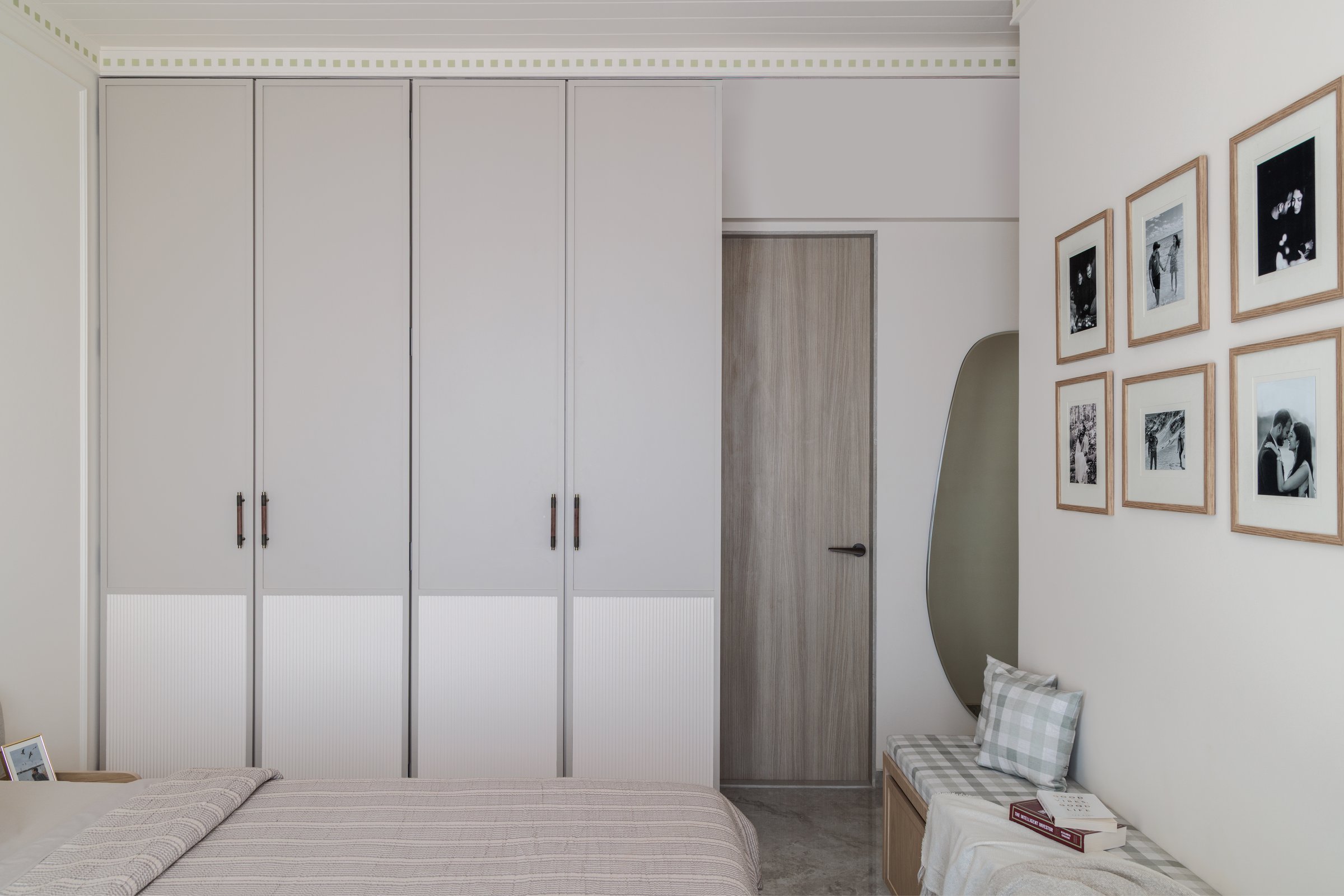 The wardrobe wall and a gallery of black-and-white photographs, personal warmth held within architectural restraint