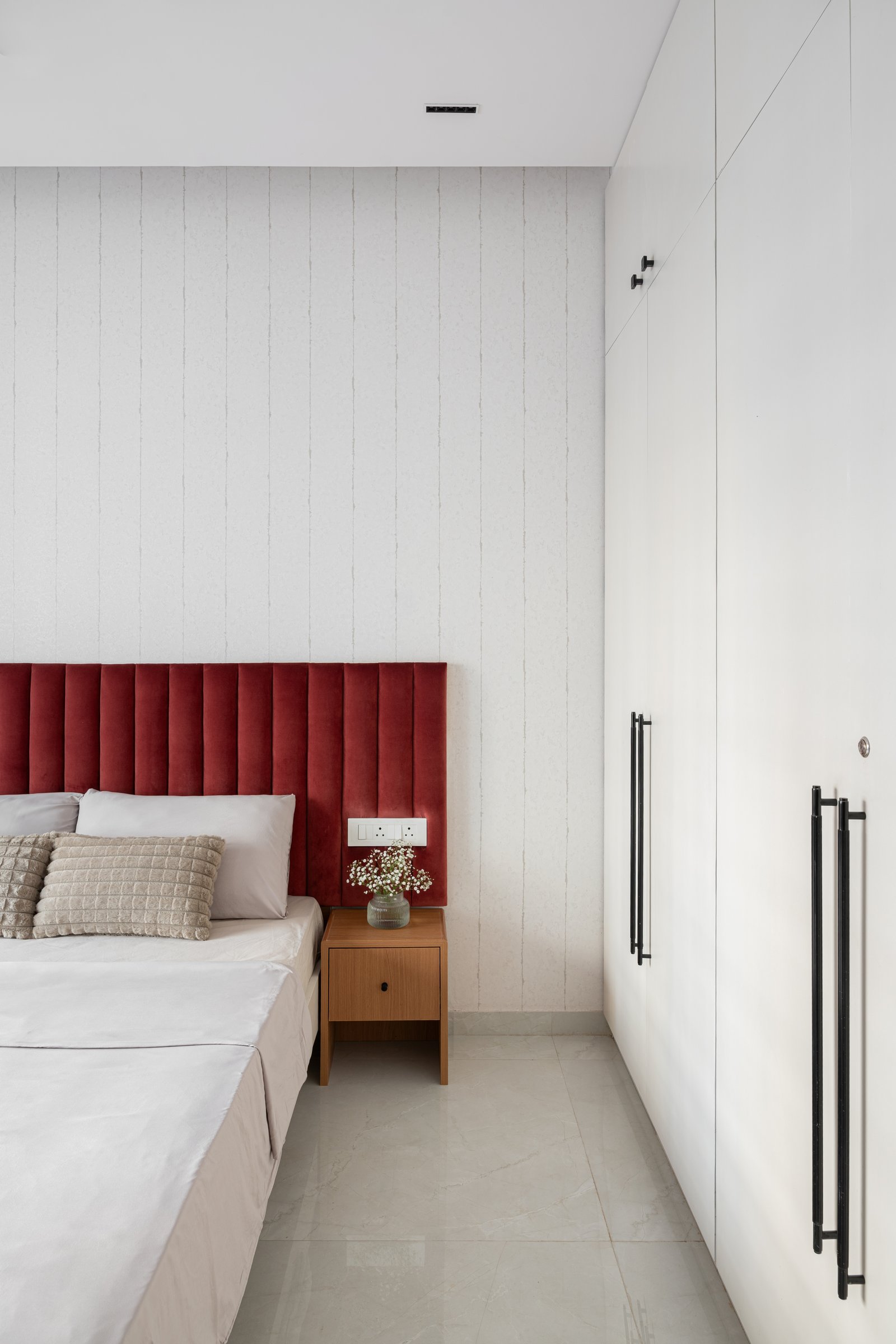 The second bedroom, where deep maroon velvet meets pale textured wallpaper