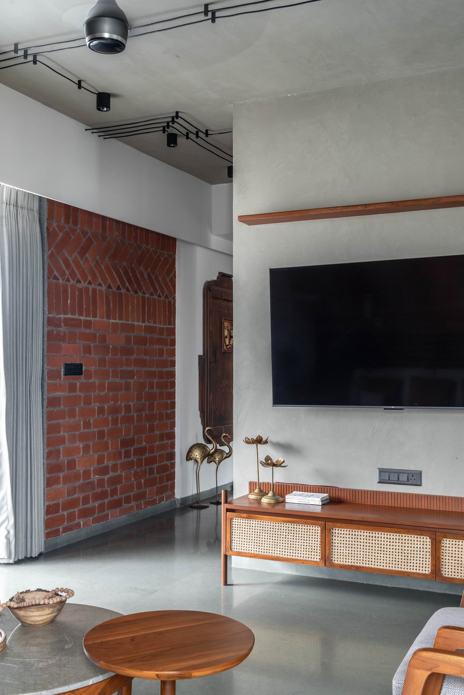 The television wall and cane-panelled console, where a continuous timber shelf links living room to kitchen