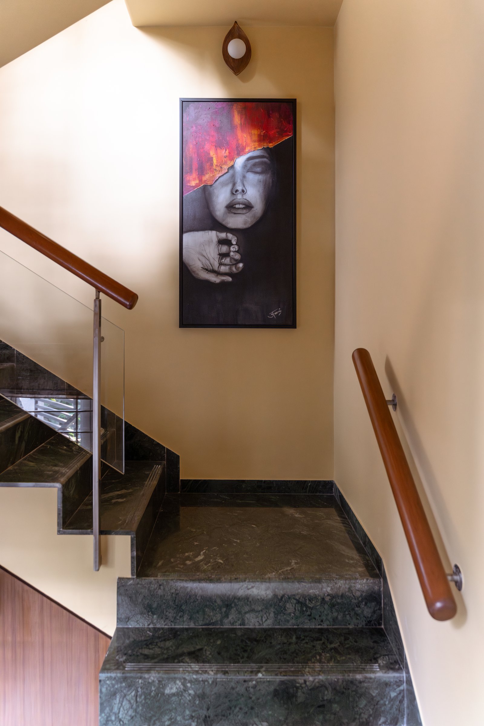 Dark marble treads and a dramatic portrait at the landing turn the staircase into a gallery pause