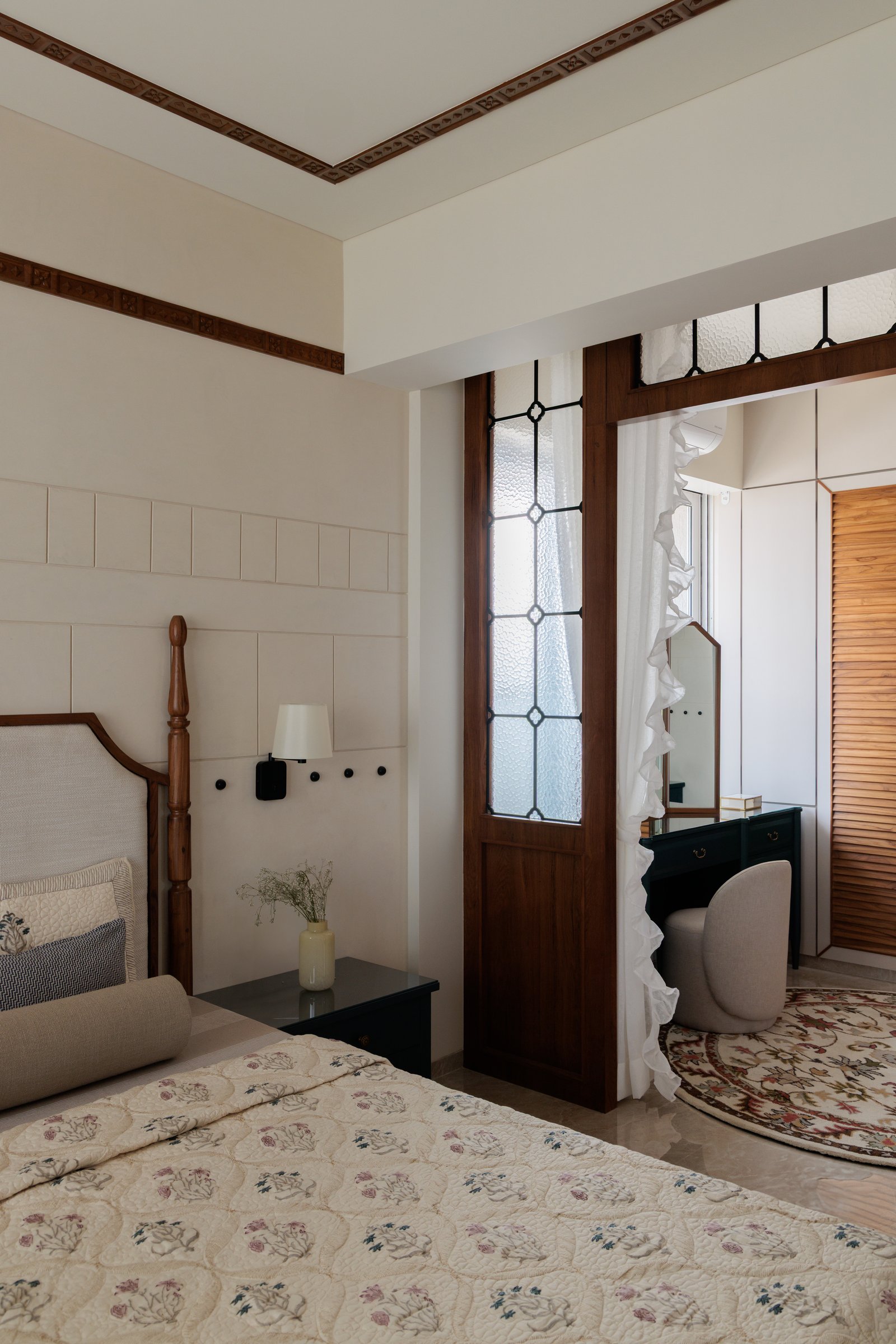 Leaded glass doors with diamond patterning filter light between the master bedroom and the dressing zone beyond