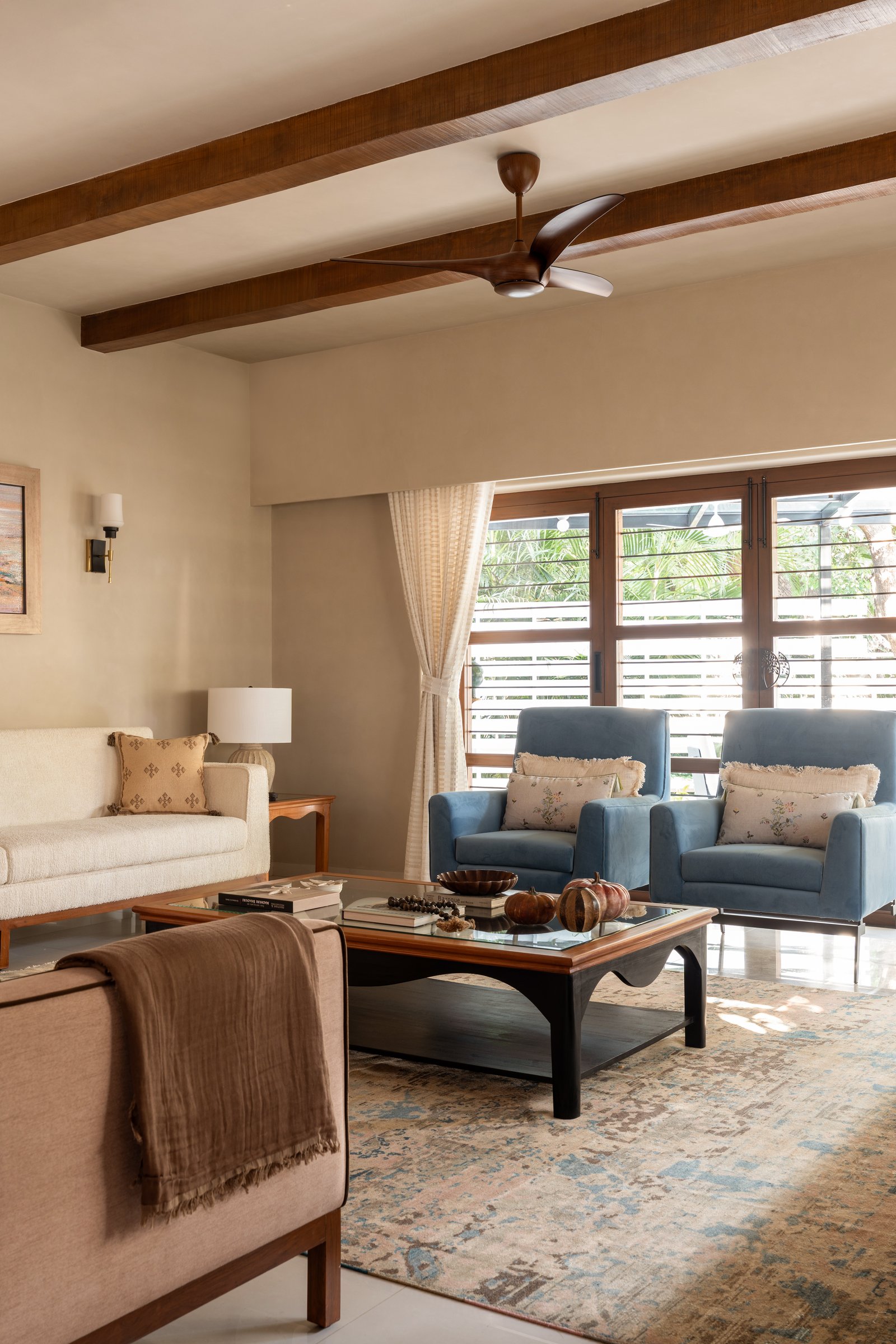 The living room's secondary seating group, where dusty blue armchairs introduce the room's only cool note