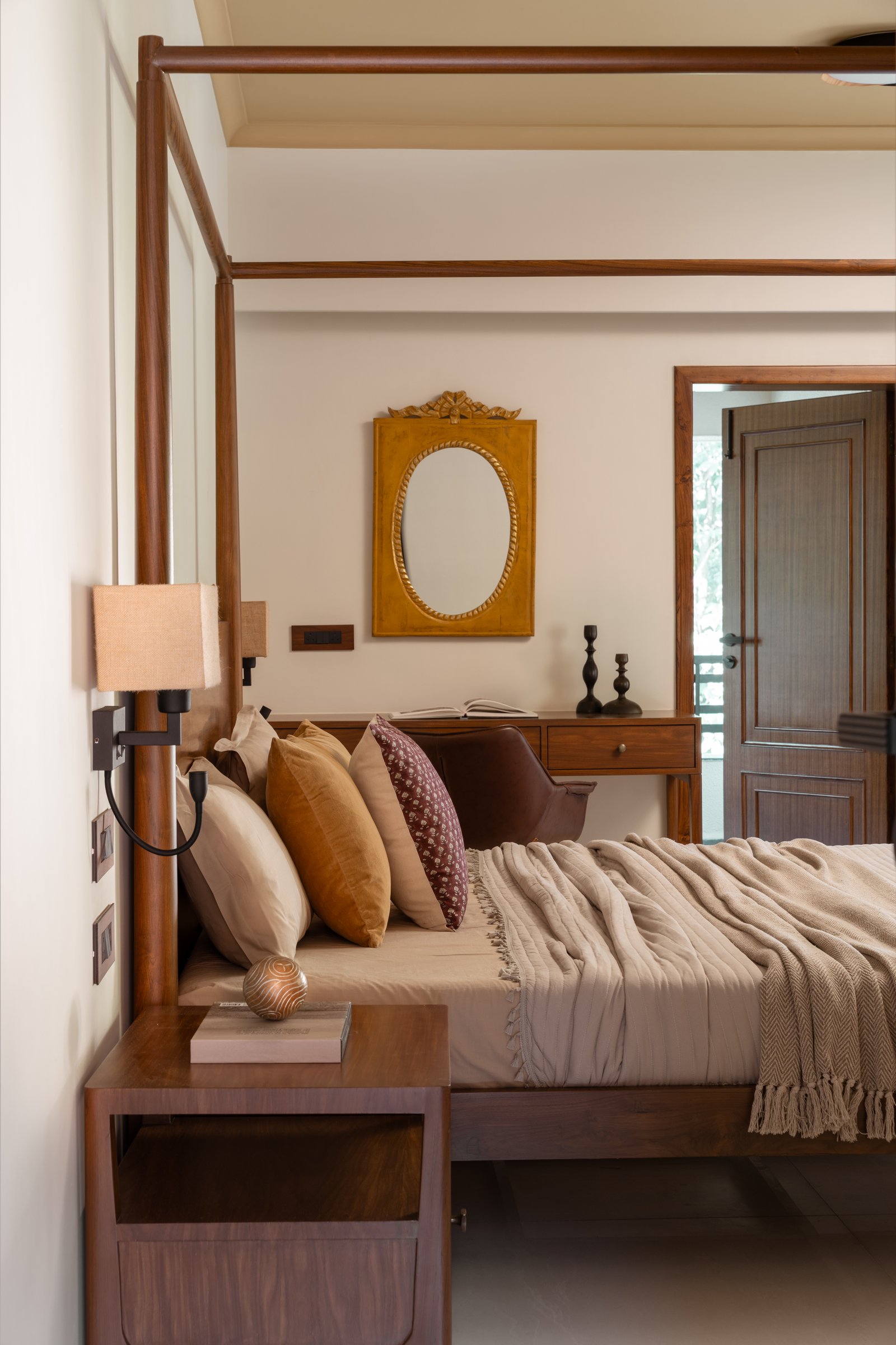 The master bedroom: a timber four-poster and gilded mirror compose a room of quiet authority