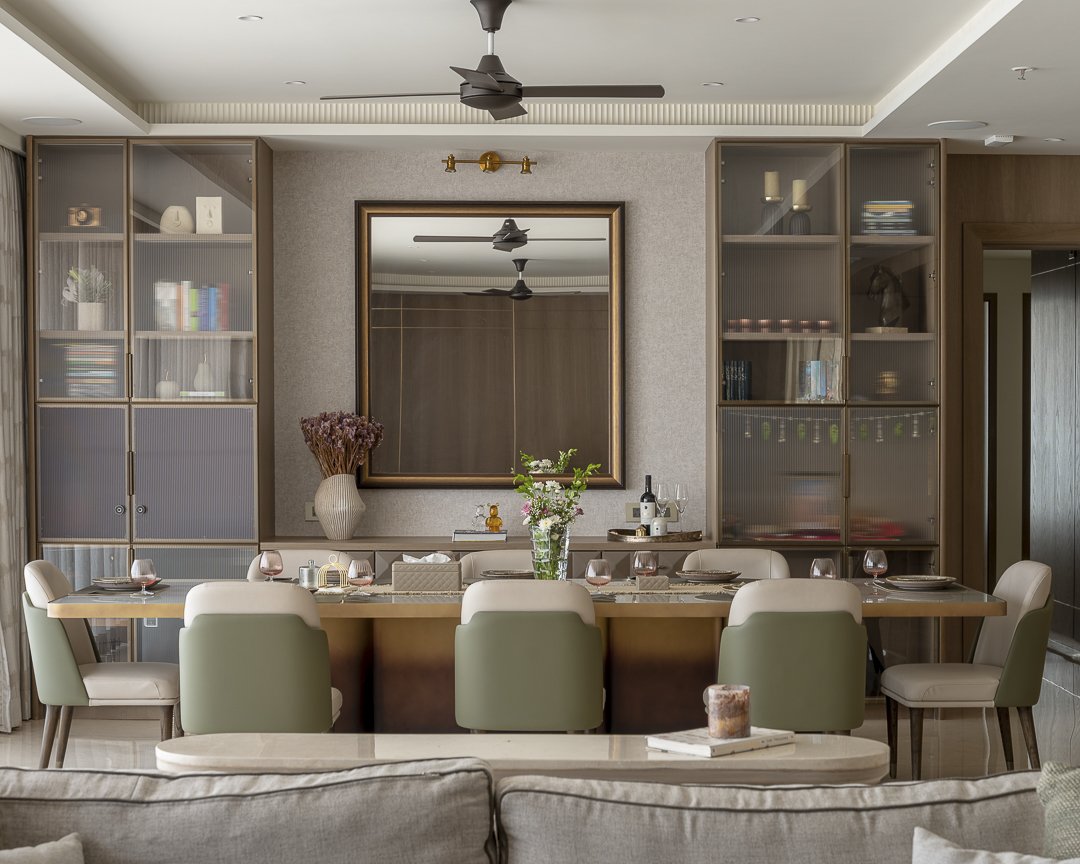 The dining area, with sage green chairs introducing the home's first tonal departure against reeded-glass display cabinets