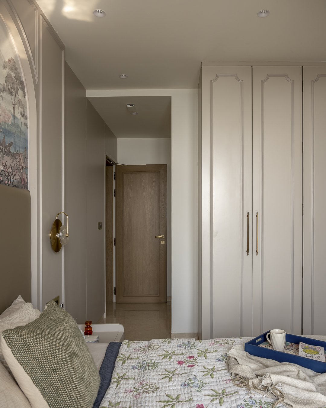 A wider view of the master bedroom, with panelled wardrobes and brass sconces completing the classical frame